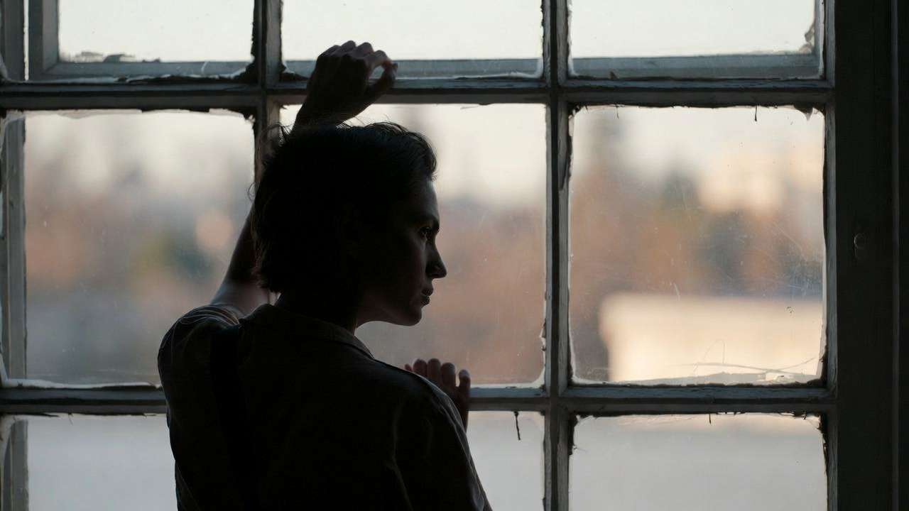 Contemplative person looking out a window, representing common challenges in practicing mindfulness and happiness.
