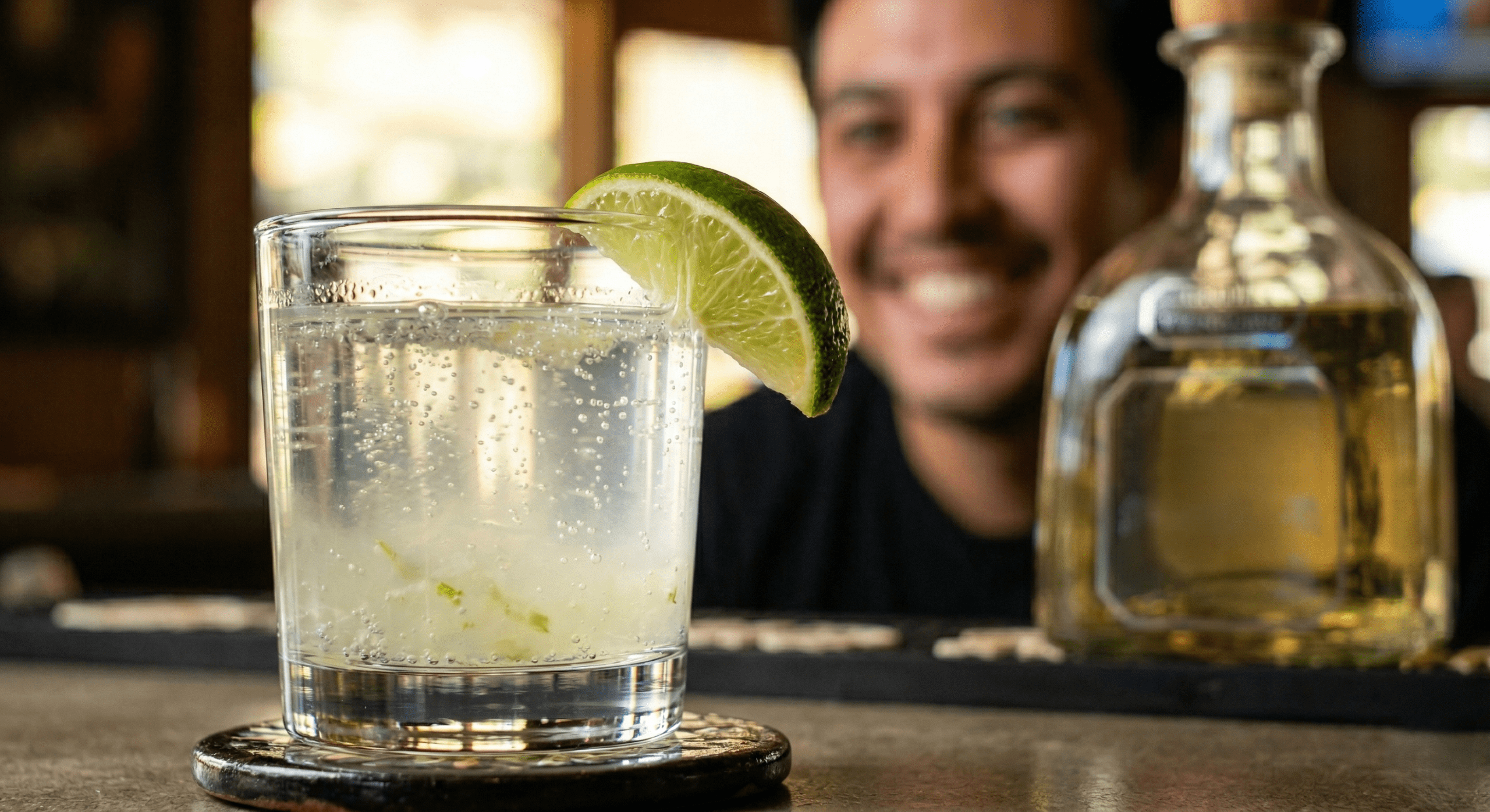 High-quality photo of a clean tequila and sparkling water cocktail with fresh lime, a healthy choice at El Camino Happy Hour. 
